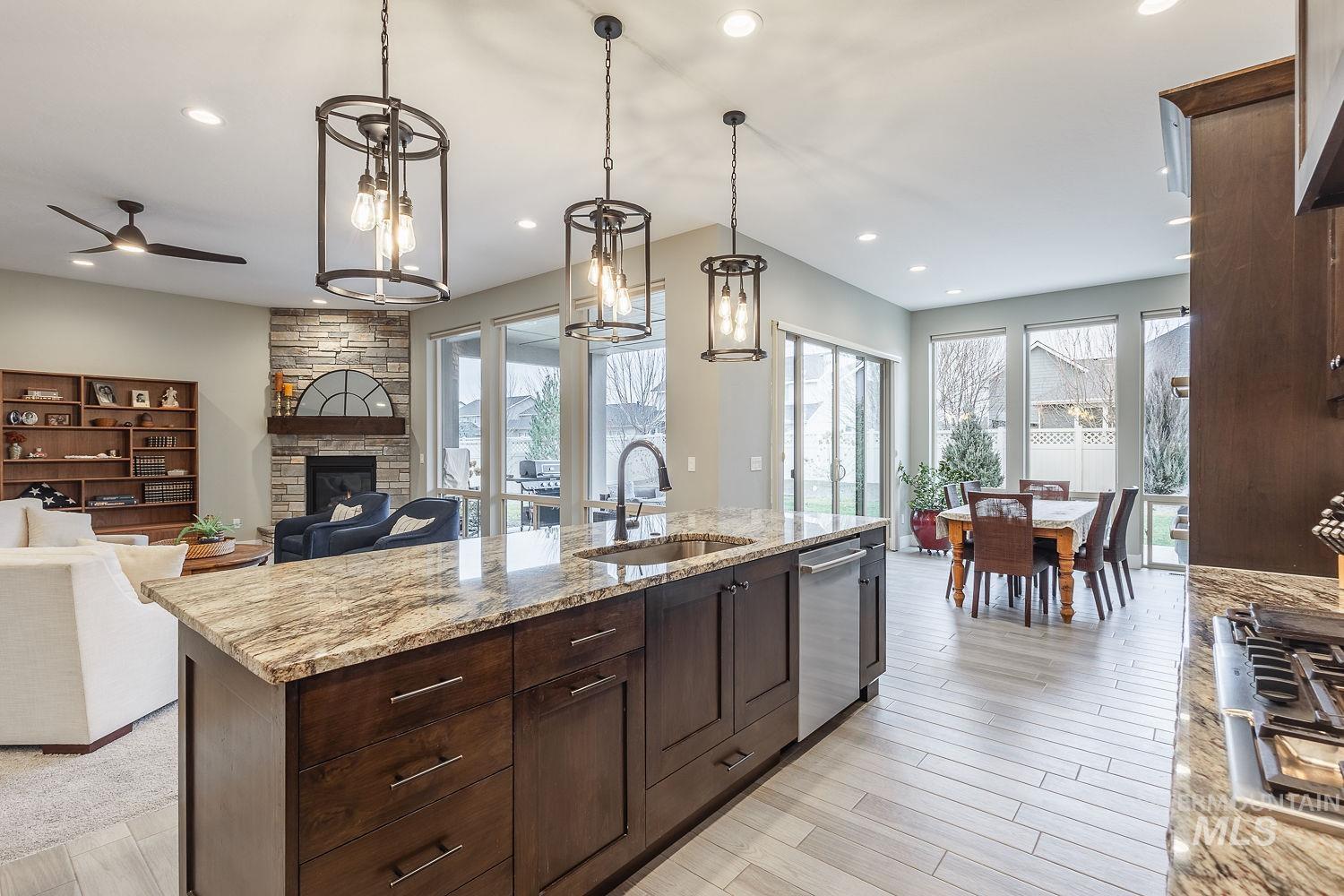 4078 West Wapoot Street Meridian, ID 83646 - Photo 13 of 46 Kitchen featuring a stone fireplace, hanging light fixtures, dark brown cabinetry, light stone countertops, and recessed lighting