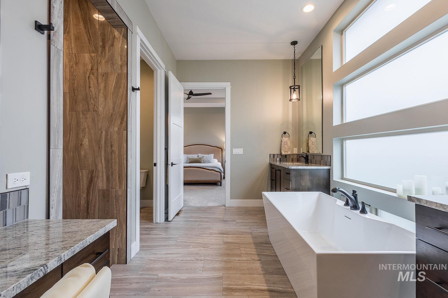 4078 West Wapoot Street Meridian, ID 83646 - Photo 22 of 46 Ensuite bathroom featuring vanity, a freestanding tub, a ceiling fan, and light wood-type flooring