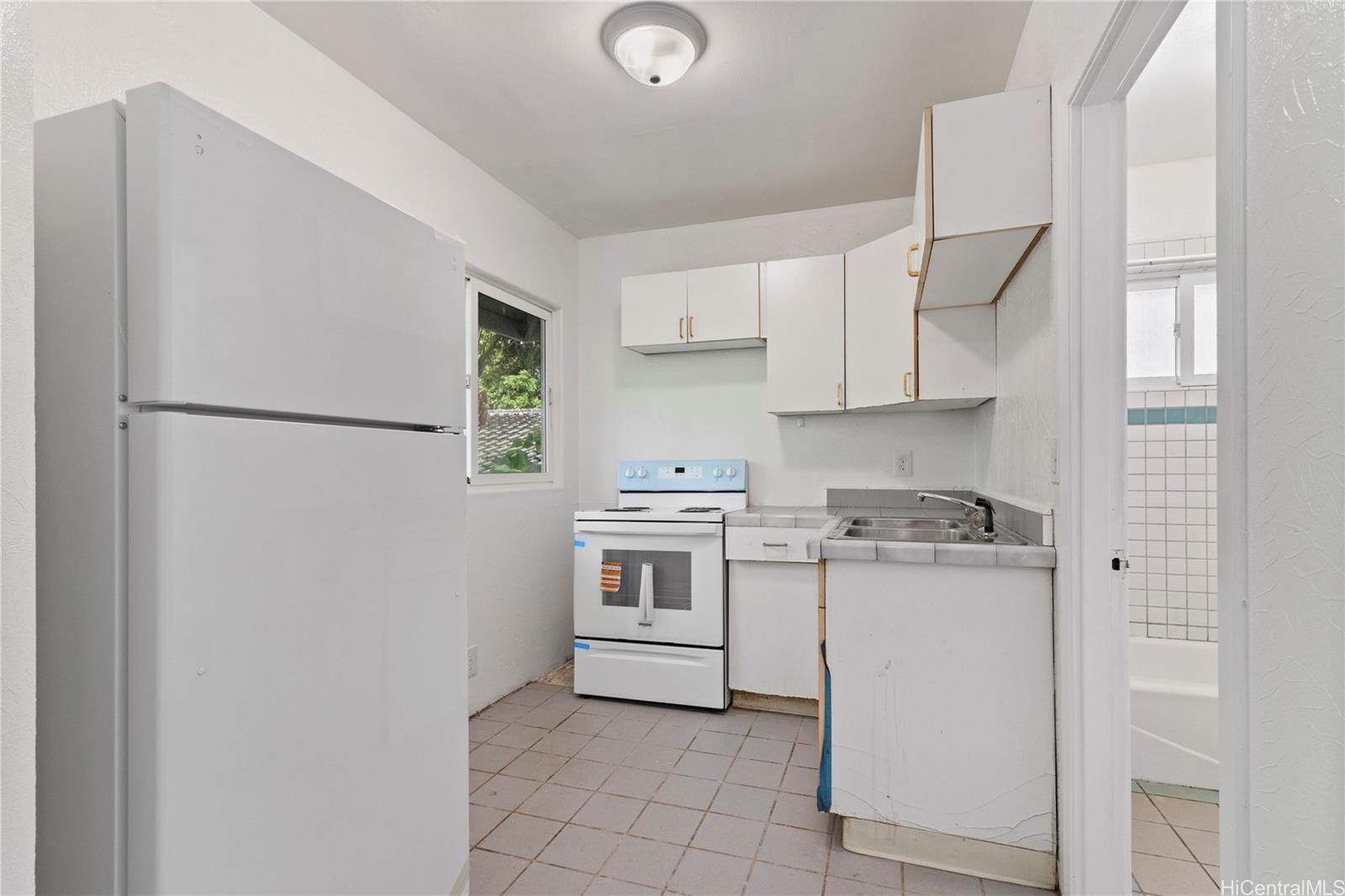 54-230 Hauula Homestead Road, Unit A Hauula, HI 96717 - Photo 14 of 22 a kitchen with stainless steel appliances granite countertop a refrigerator sink and white cabinets