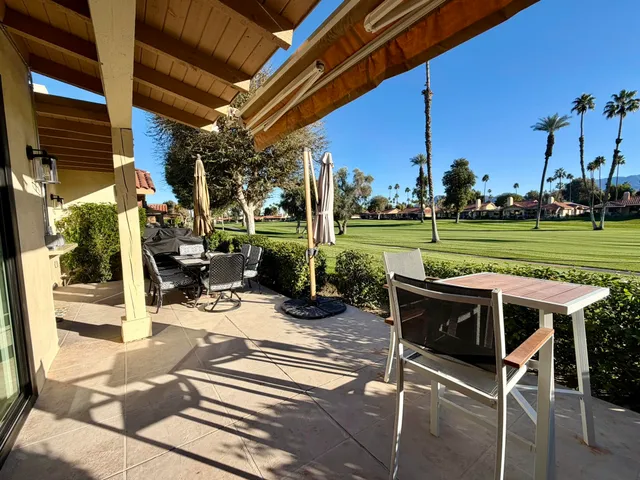 a view of a patio with a table chairs potted plants and a palm tree