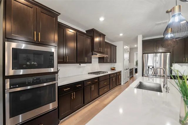 a large kitchen with stainless steel appliances wooden cabinets and a stove top oven