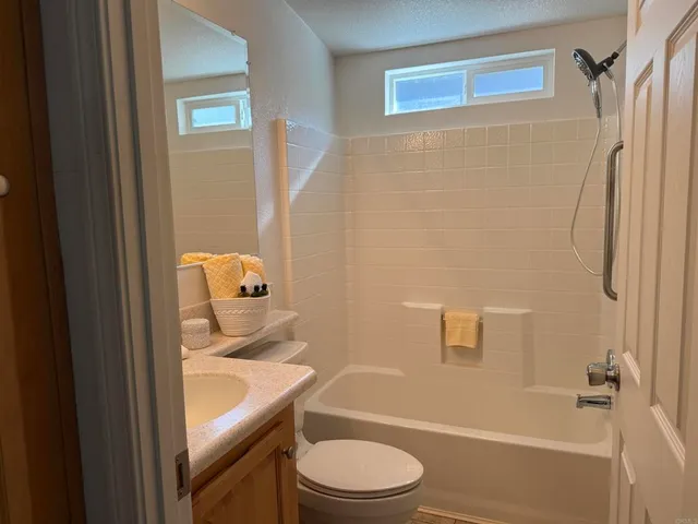 a bathroom with a granite countertop toilet a sink and shower