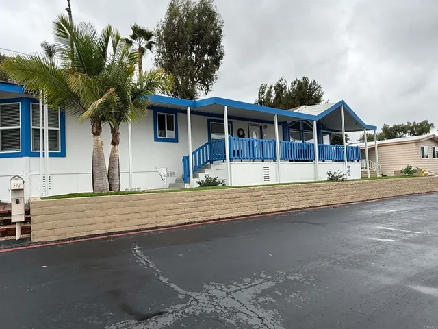 front view of house with a yard and palm trees