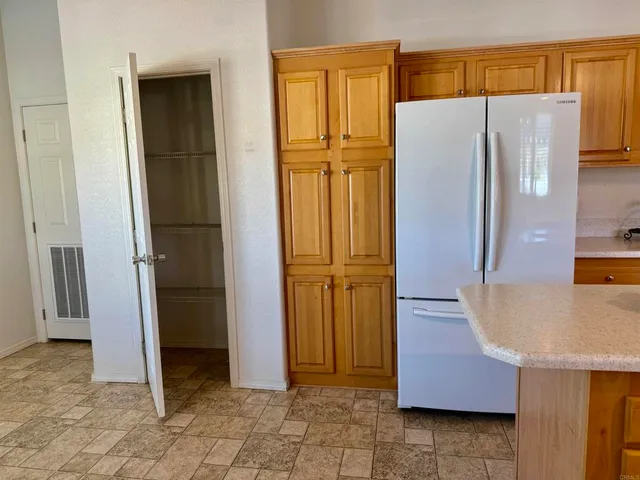 a view of a refrigerator in kitchen and an empty room