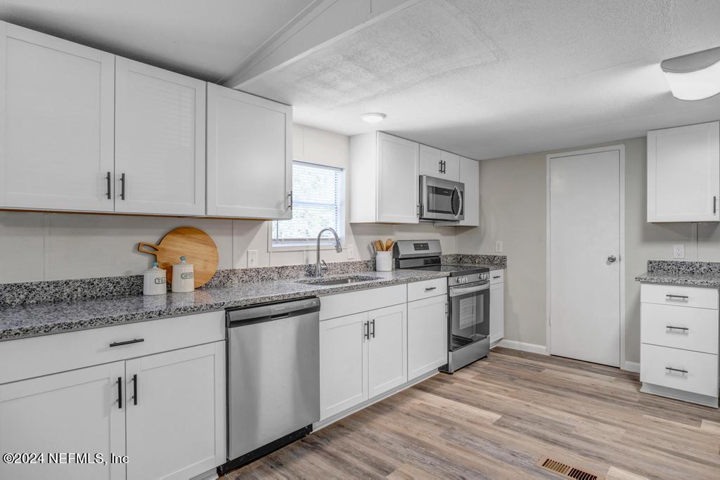 5557 Acadia Street Keystone Heights, FL 32656 - Photo 12 of 32 a kitchen with granite countertop white cabinets and stainless steel appliances