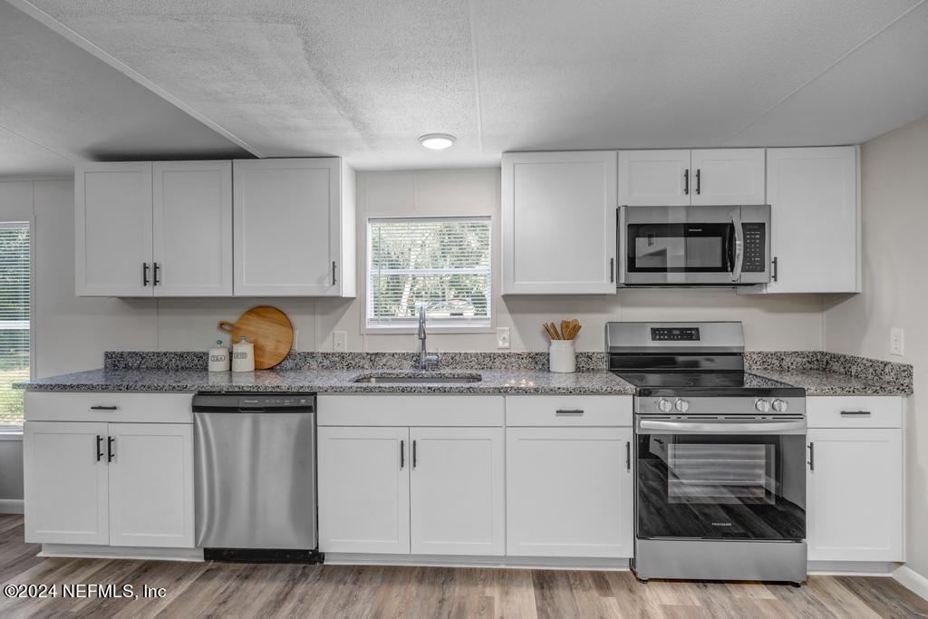 5557 Acadia Street Keystone Heights, FL 32656 - Photo 14 of 32 a kitchen with granite countertop white cabinets sink and stainless steel appliances
