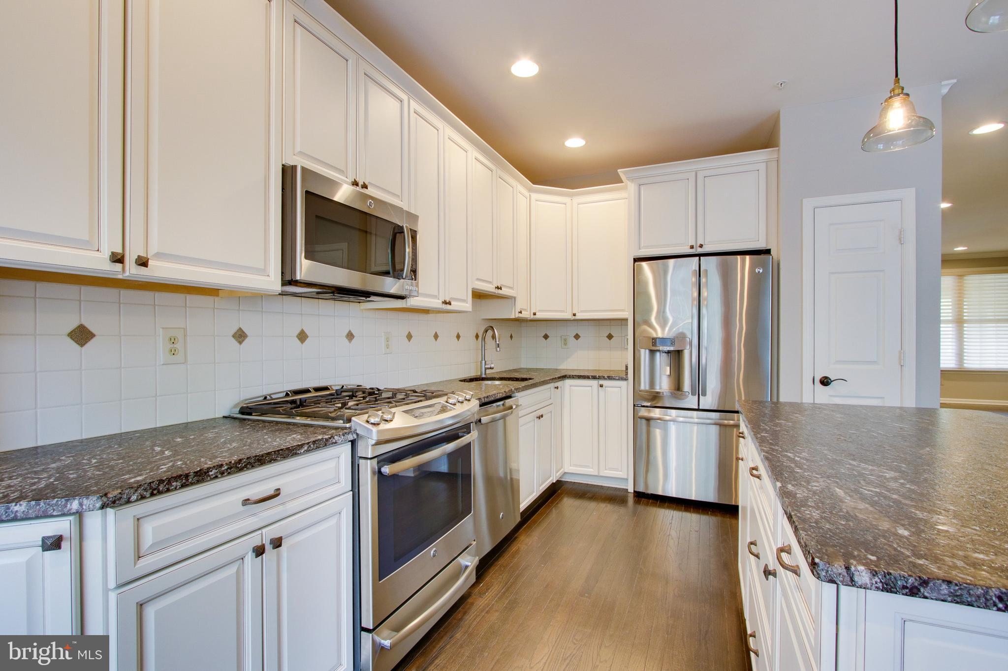 8818 Howard Forest Lane Baltimore, MD 21208 - Photo 11 of 31 a kitchen with stainless steel appliances granite countertop a stove a refrigerator and a microwave