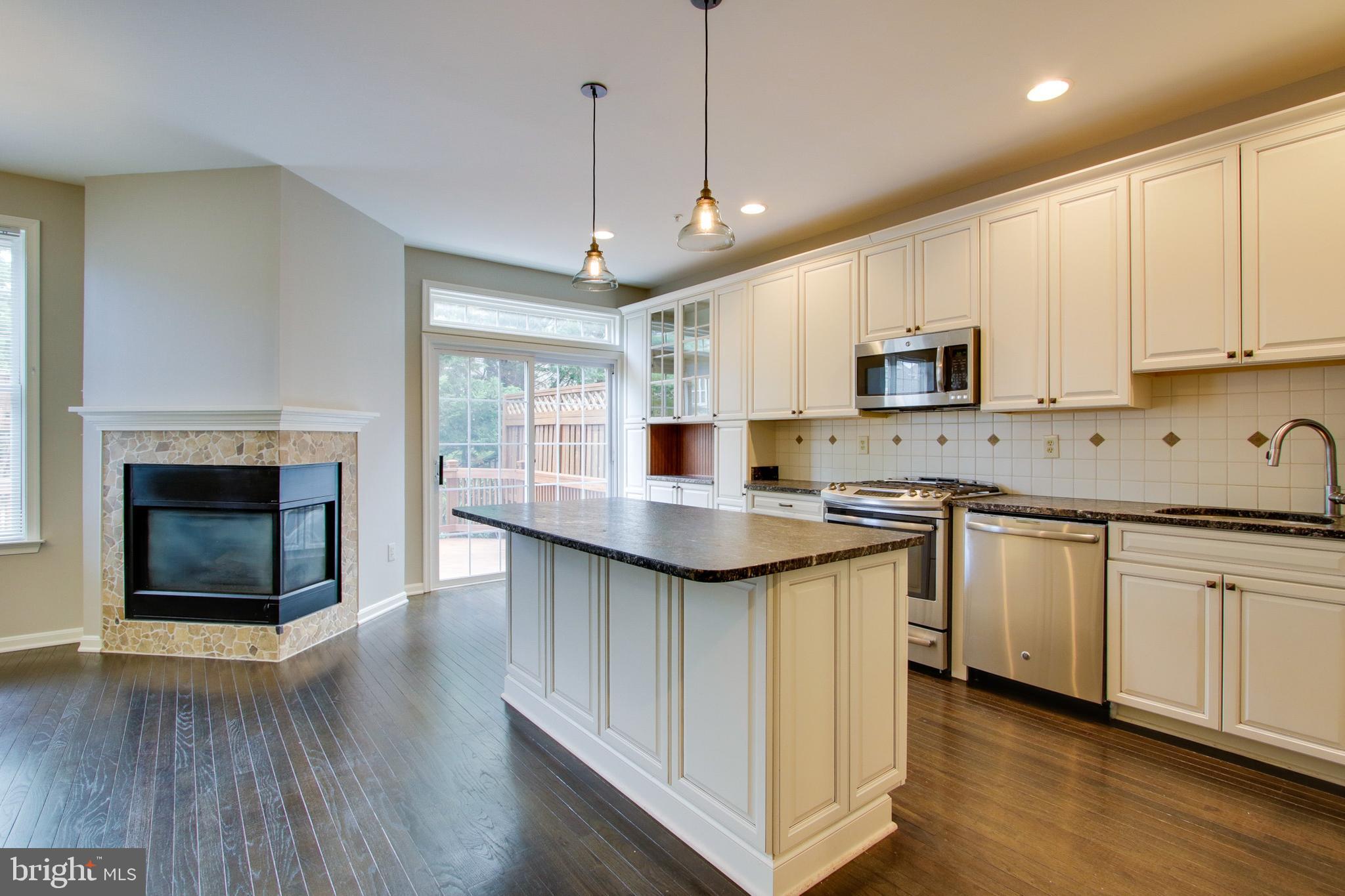 8818 Howard Forest Lane Baltimore, MD 21208 - Photo 6 of 31 a kitchen with kitchen island granite countertop a stove a sink and a microwave