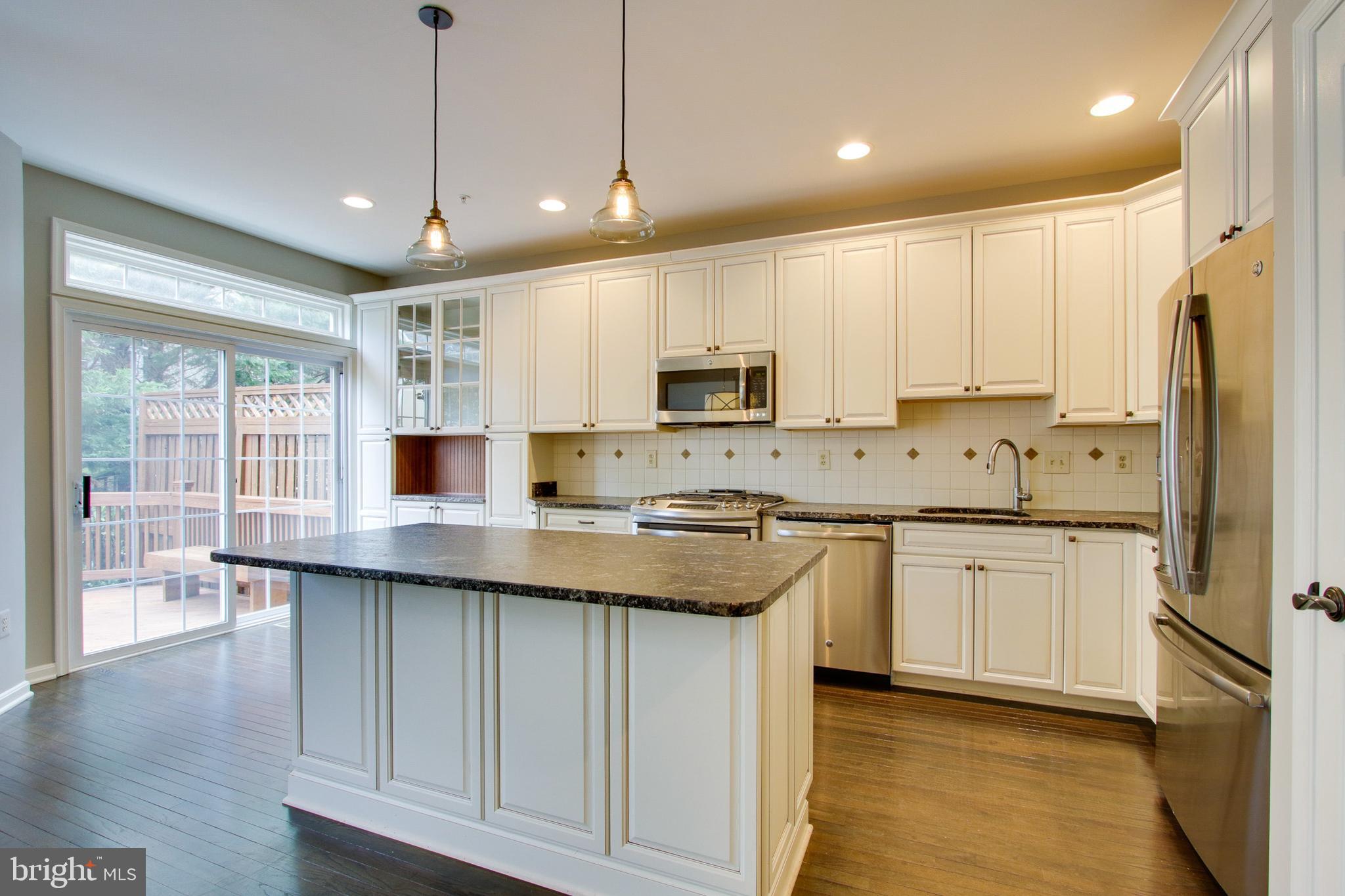8818 Howard Forest Lane Baltimore, MD 21208 - Photo 7 of 31 a kitchen with stainless steel appliances granite countertop a sink a stove a refrigerator cabinets and wooden floor
