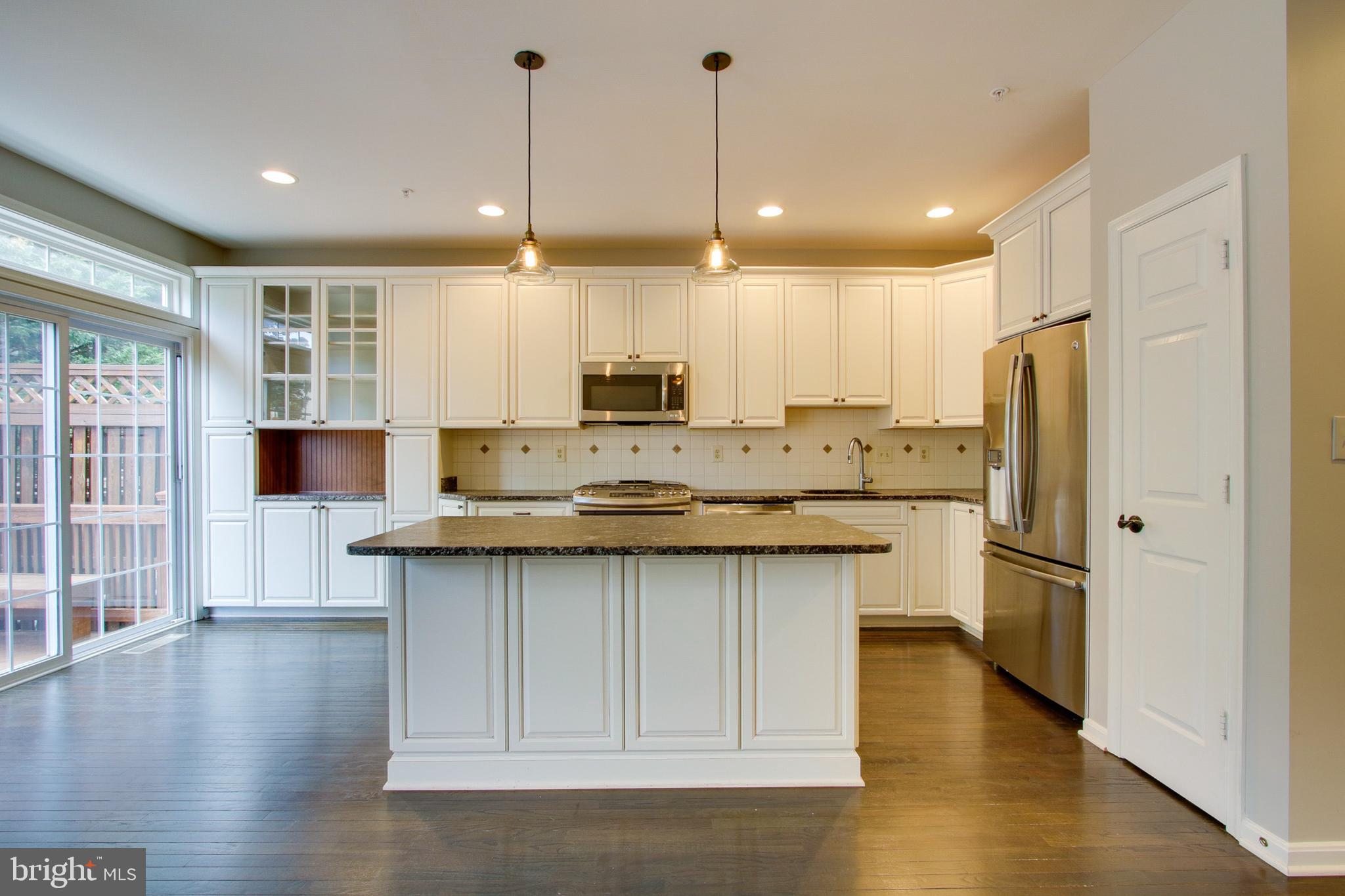 8818 Howard Forest Lane Baltimore, MD 21208 - Photo 8 of 31 a kitchen with stainless steel appliances granite countertop a refrigerator a sink dishwasher a stove and white cabinets with wooden floor