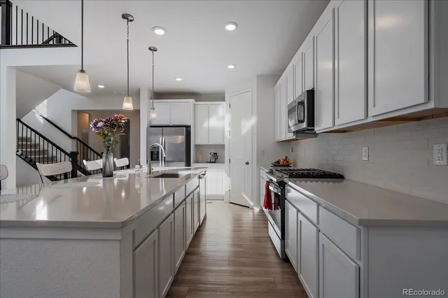 a kitchen with stainless steel appliances granite countertop a stove a sink a oven and a kitchen island with wooden floor