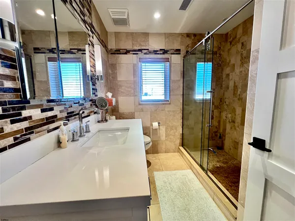 a bathroom with a sink a toilet a mirror and shower