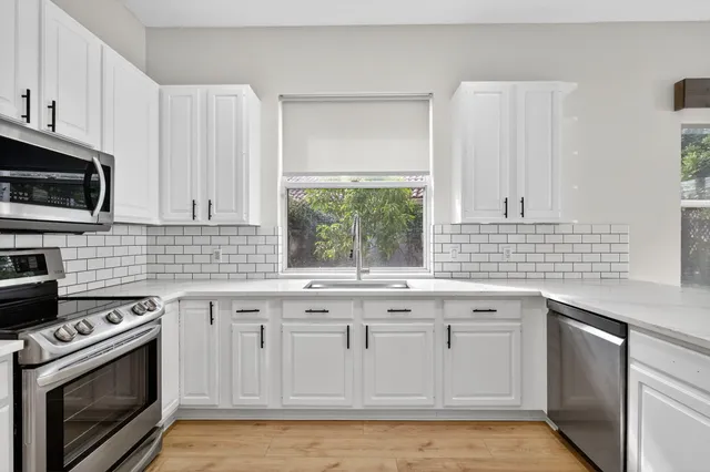 a kitchen with stainless steel appliances granite countertop a sink stove and microwave
