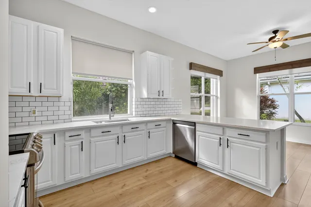 a large white kitchen with a sink cabinets and wooden floor