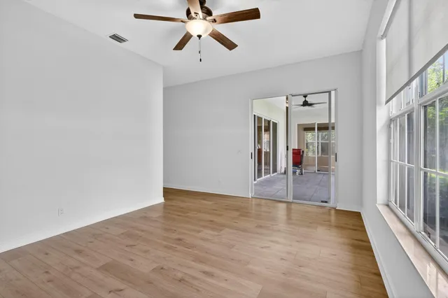 a view of a hallway with wooden floor and a chandelier fan