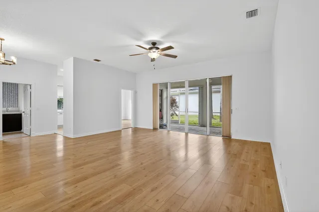 a view of an empty room with window and wooden floor