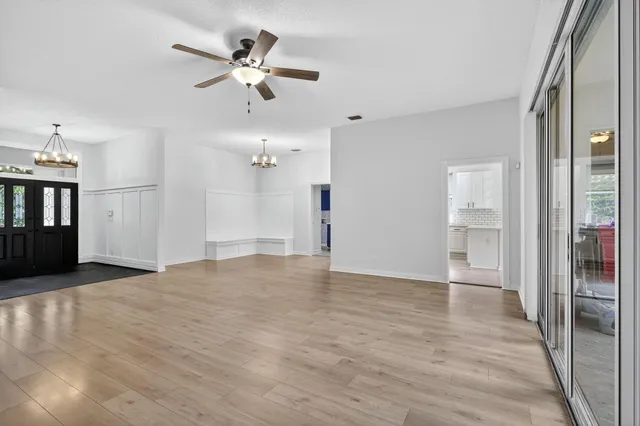 a view of an empty room with window and a kitchen