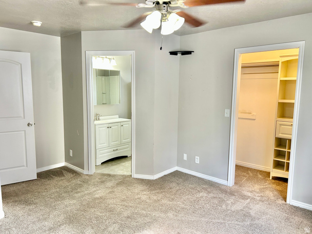 672 West 720 South Logan, UT 84321 - Photo 5 of 15 Carpeted interior space featuring a ceiling fan with integrated lighting, a full bathroom with a white vanity and mirror, and a walk-in closet with built-in shelving