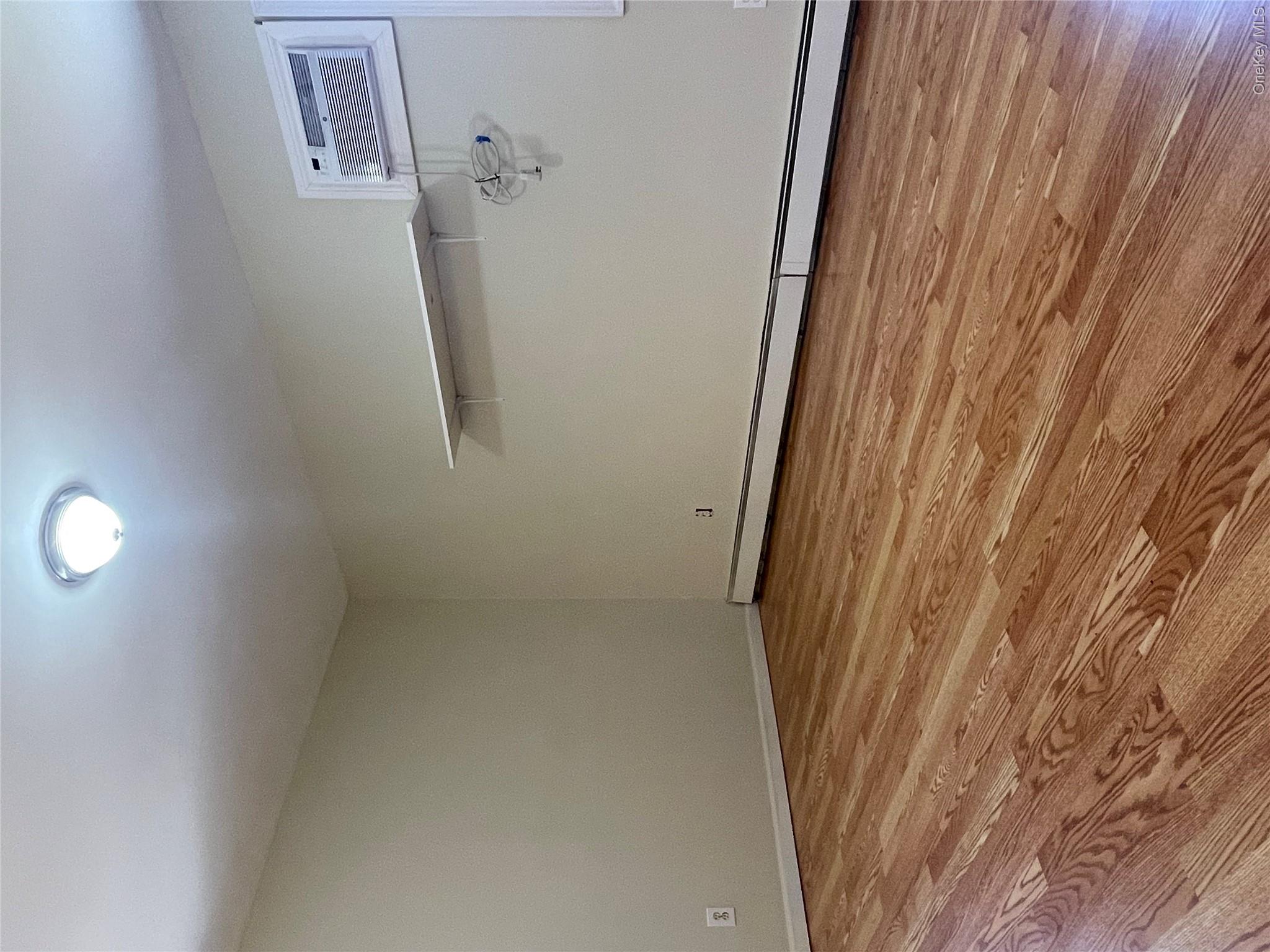 171 Hounslow Road Shirley, NY 11967 - Photo 16 of 31 a view of an empty room with wooden floor and cabinet