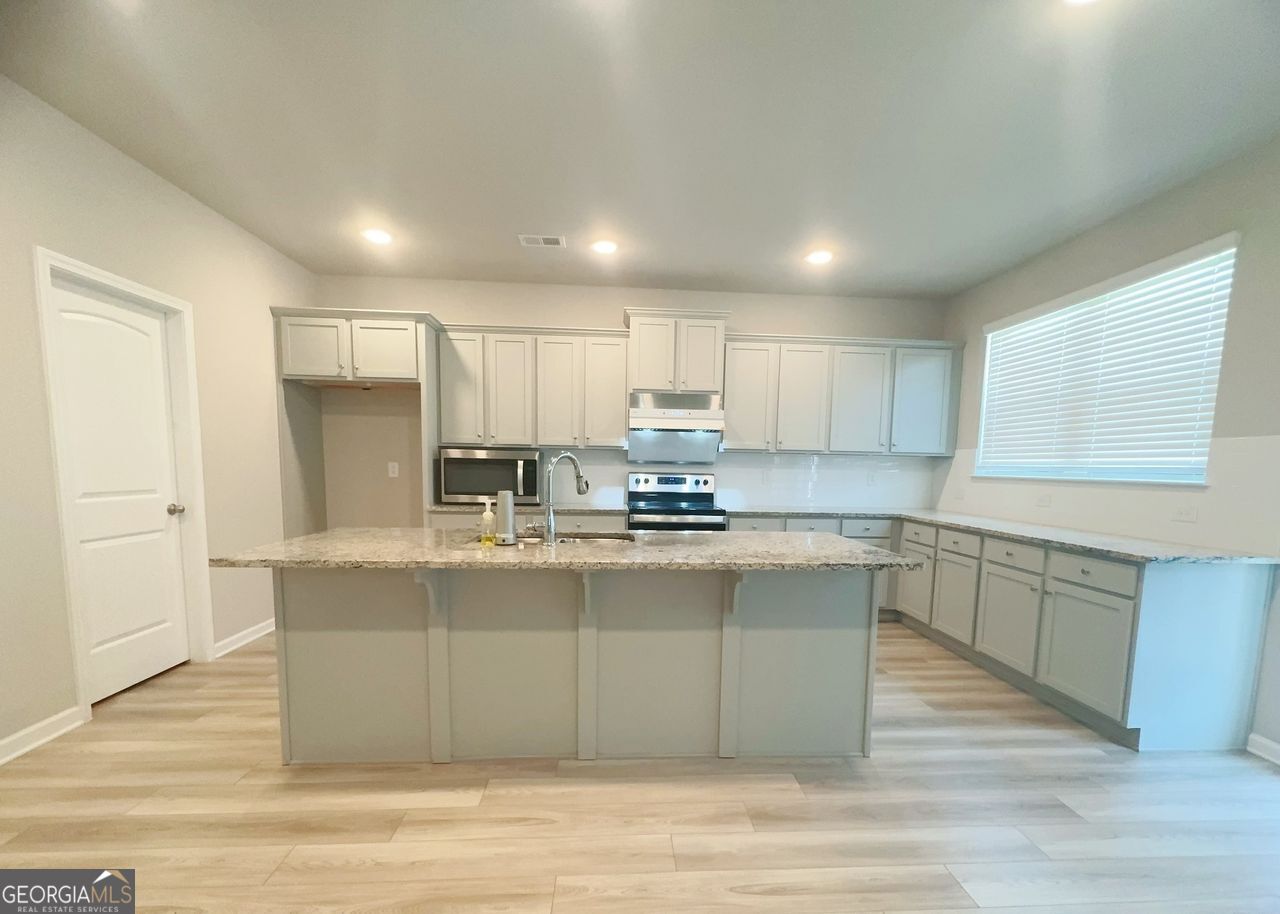 446 Sawmill Trace Hampton, GA 30228 - Photo 4 of 15 a large kitchen with stainless steel appliances granite countertop a stove a sink dishwasher and a refrigerator with wooden floor