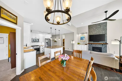 a view of a dining room kitchen with furniture a fireplace wooden floor and a chandelier
