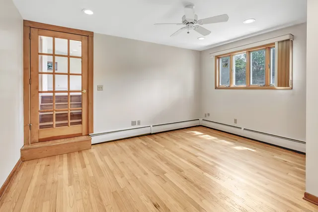 an empty room with wooden floor chandelier and windows