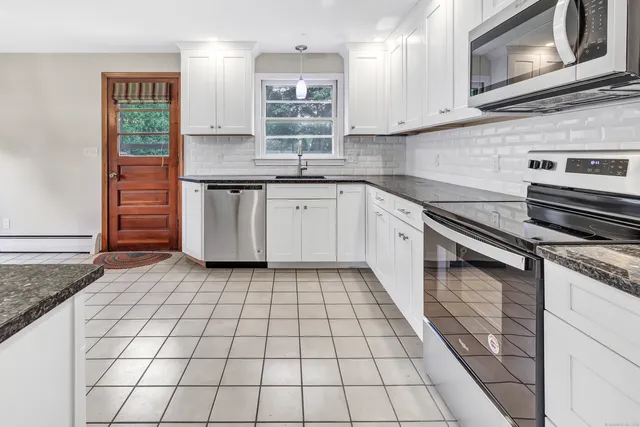 a kitchen with stainless steel appliances granite countertop a stove a sink and a microwave