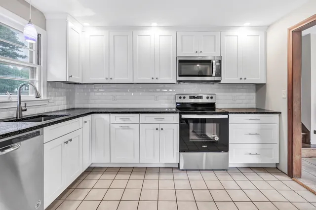 a kitchen with granite countertop white cabinets and stainless steel appliances
