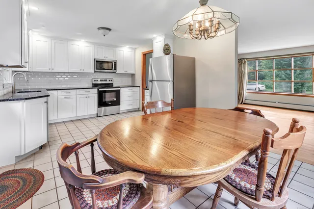 a kitchen with stainless steel appliances granite countertop a dining table chairs and a refrigerator