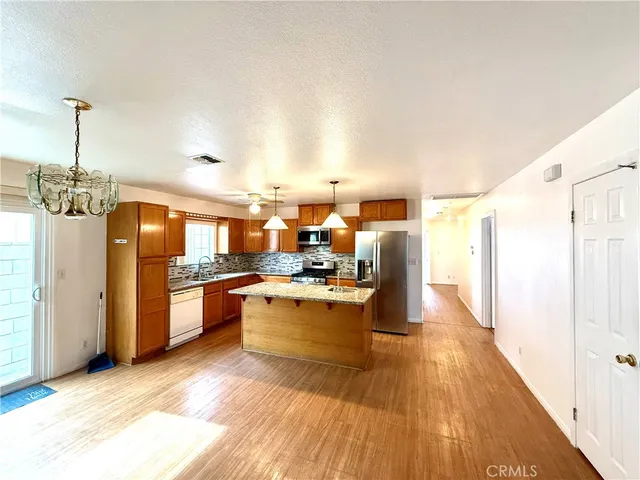 a kitchen with stainless steel appliances granite countertop a stove top oven a sink dishwasher a dining table and chairs with wooden floor