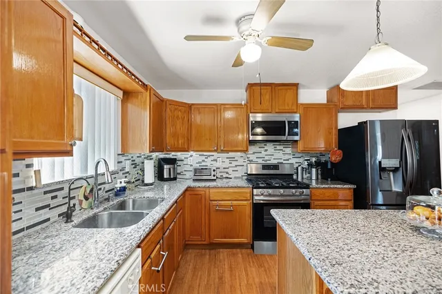 a kitchen with stainless steel appliances granite countertop a stove top oven a sink dishwasher a dining table and chairs with wooden floor