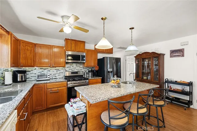 a kitchen with stainless steel appliances granite countertop a stove top oven a sink a dining table and chairs with wooden floor