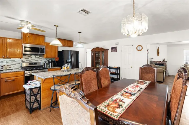 a kitchen with stainless steel appliances kitchen island granite countertop a stove a sink dishwasher a dining table and chairs with wooden floor