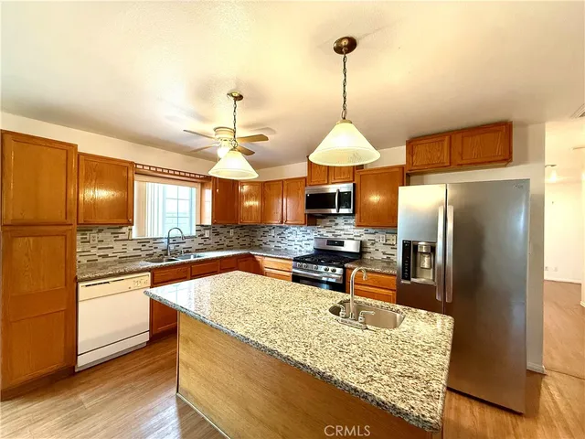 a view of a big room with wooden floor a ceiling fan and windows