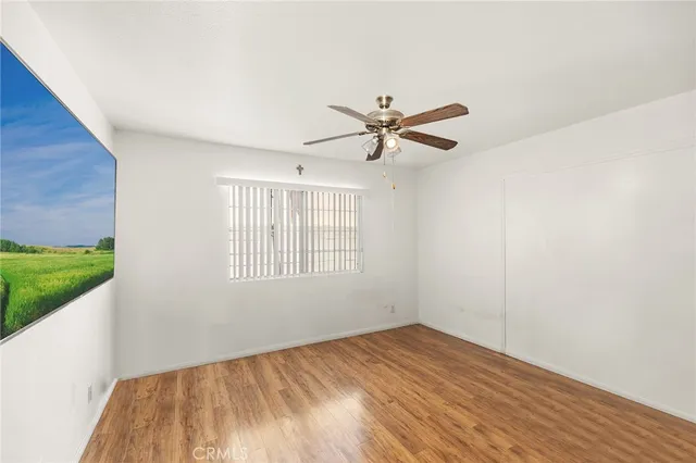 a view of a big room with wooden floor a ceiling fan and windows