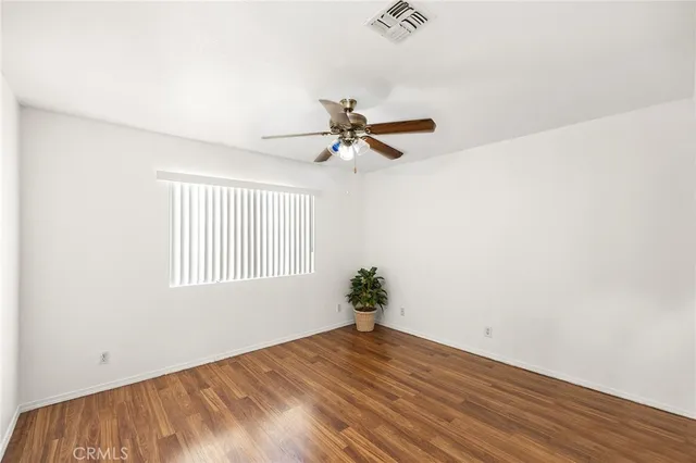 a view of a room with wooden floor and a ceiling fan