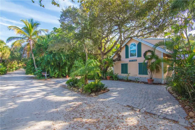 a front view of a house with a yard and a large tree