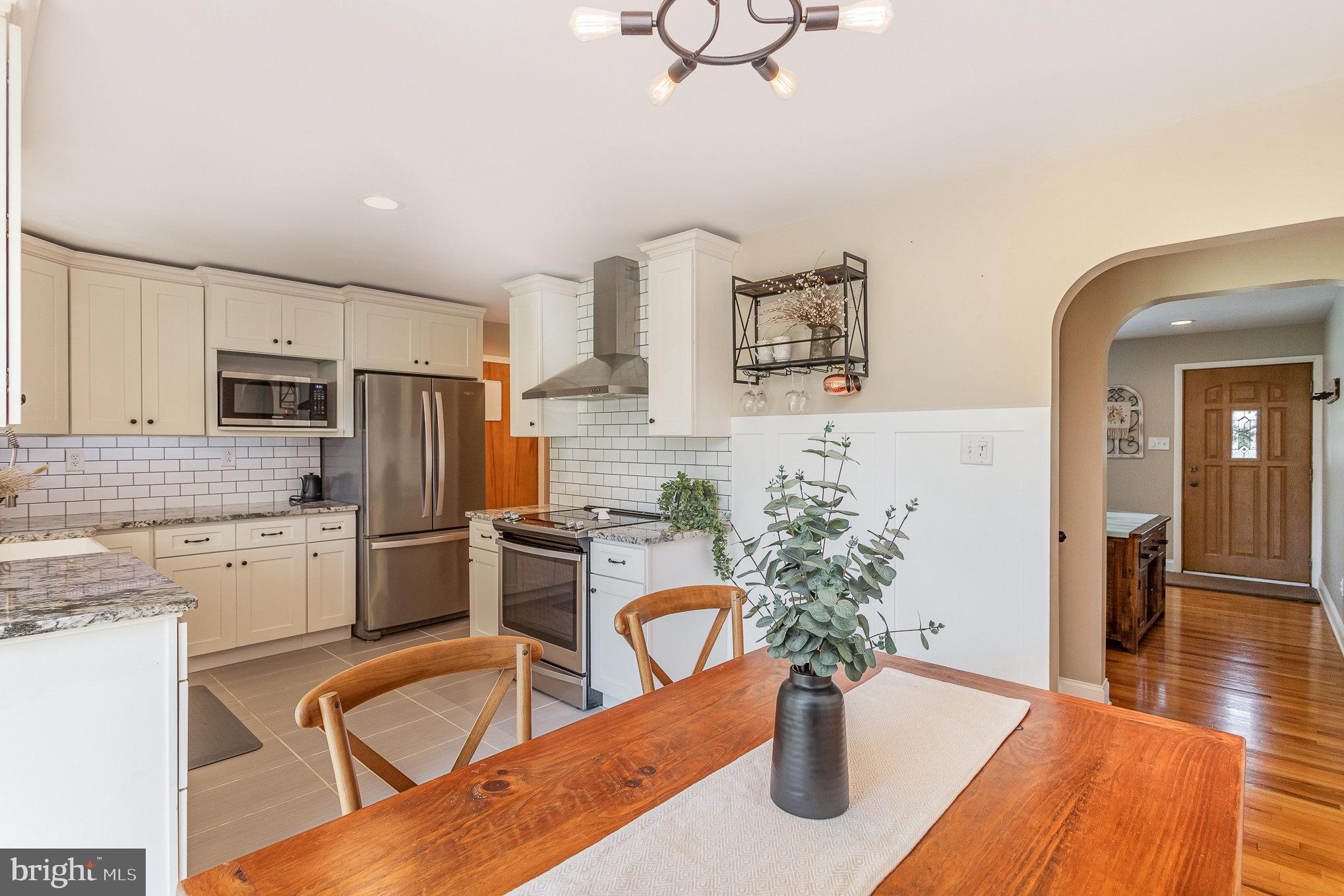 1556 Lambeth Road Lancaster, PA 17601 - Photo 10 of 42 a kitchen with stainless steel appliances granite countertop a refrigerator a stove a sink dishwasher a dining table and chairs with wooden floor