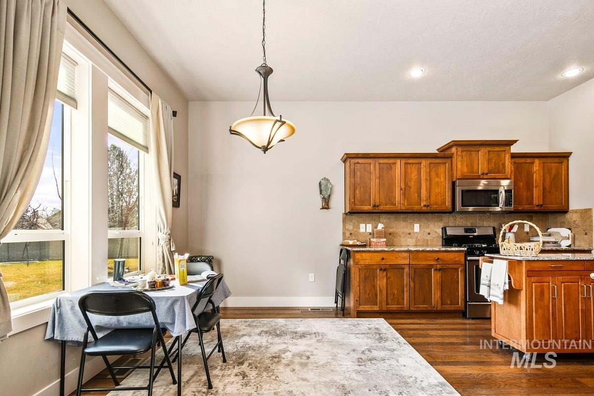 1213 West Lowry Street Meridian, ID 83646 - Photo 16 of 38 Kitchen featuring wood finish cabinets, range with gas cooktop, decorative light fixtures, light stone countertops, and stainless steel microwave