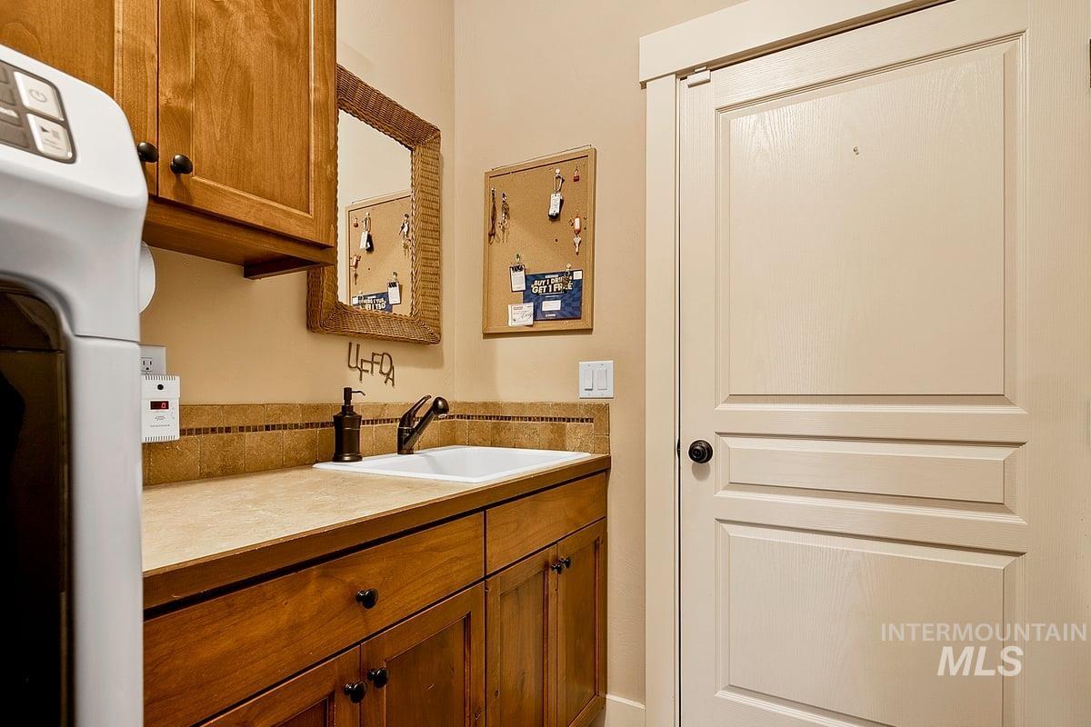 1213 West Lowry Street Meridian, ID 83646 - Photo 30 of 38 Bar area featuring wood finish cabinetry, washer / dryer, and light countertops