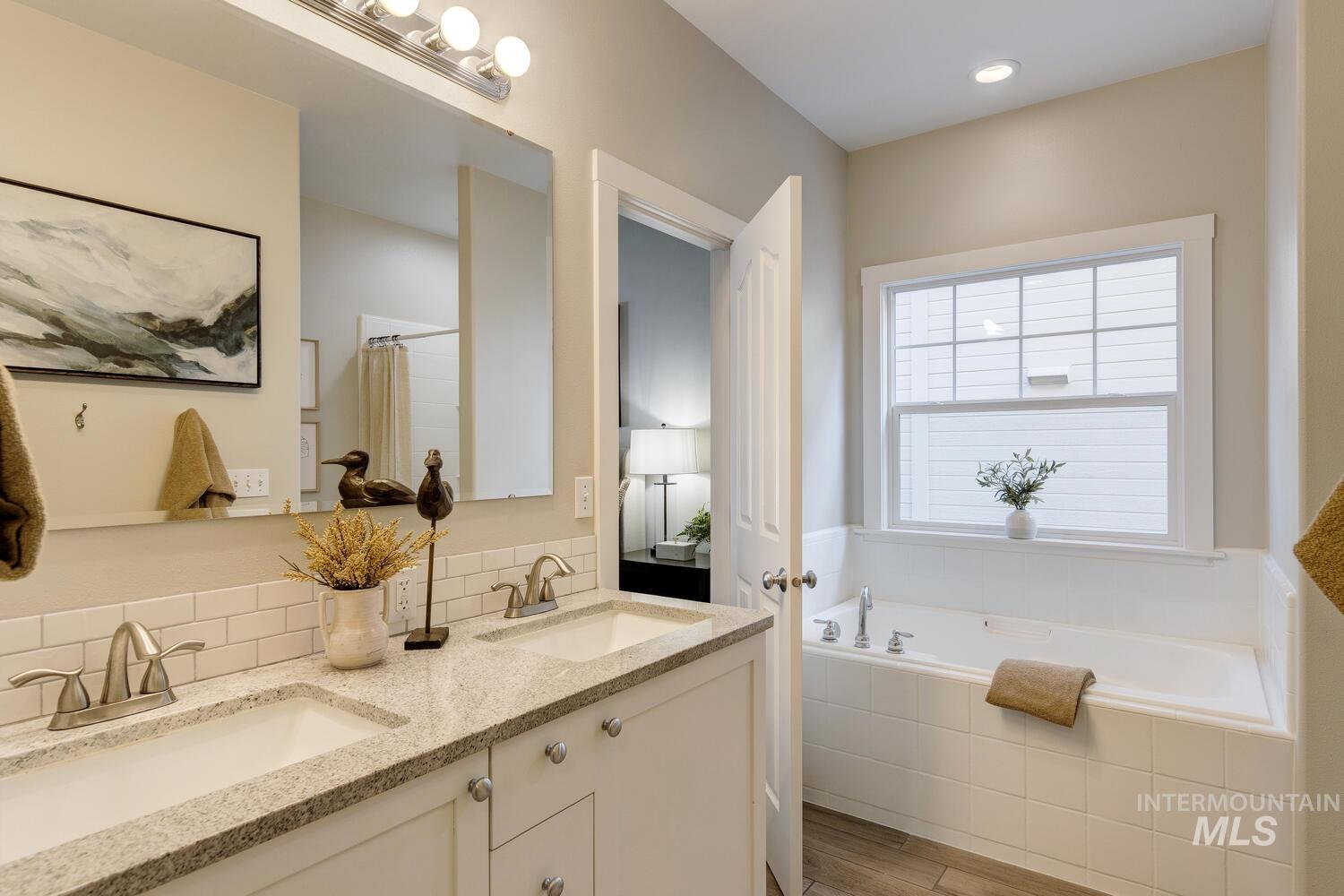 5572 West School Ridge Road Boise, ID 83714 - Photo 18 of 50 Full bathroom with double vanity, a bath, curtained shower, backsplash, and light wood finished floors