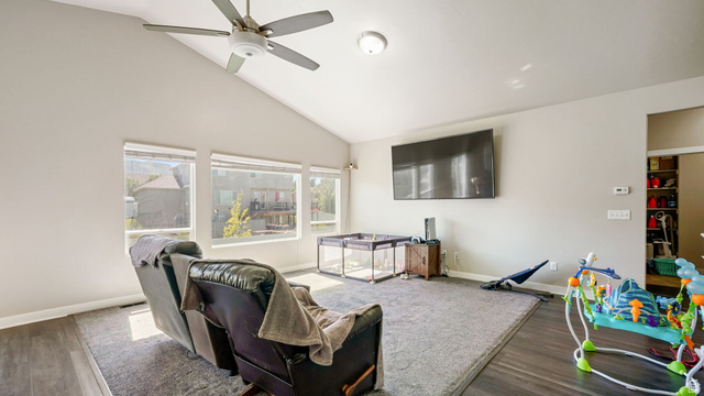 6062 Spring Street Stansbury Park, UT 84074 - Photo 7 of 36 Living room featuring vaulted ceilings, multiple windows for great lighting, new carpet, LVP flooring, a ceiling fan, and a mounted light fixture