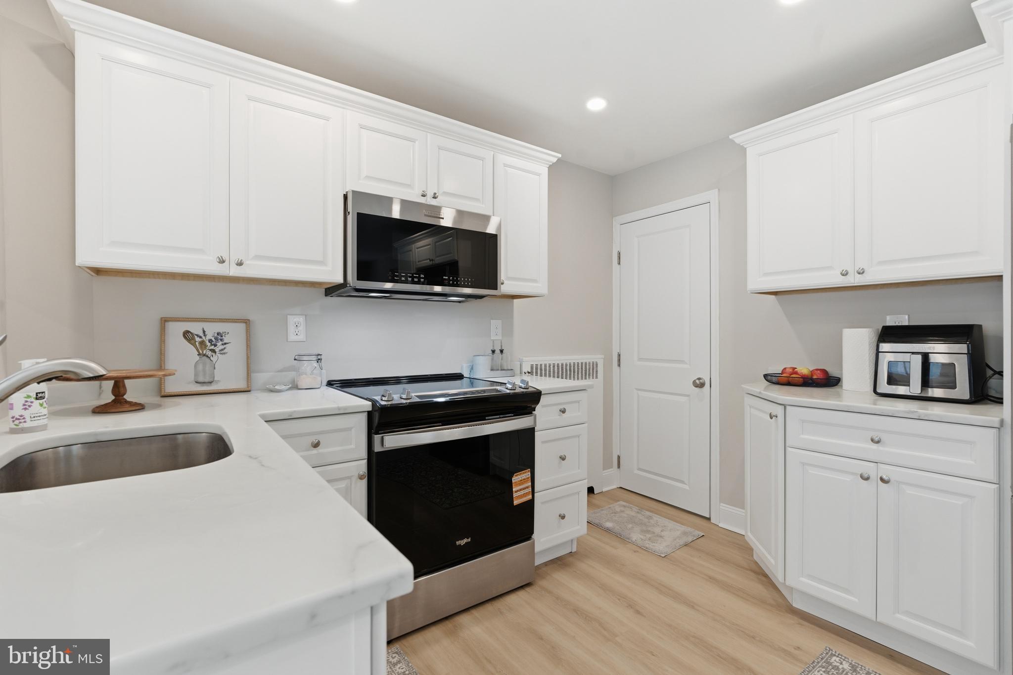 308 Canterbury Road Havertown, PA 19083 - Photo 11 of 26 a kitchen with granite countertop a sink and a stove top oven with wooden floor