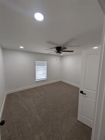 an empty room with a ceiling fan and window