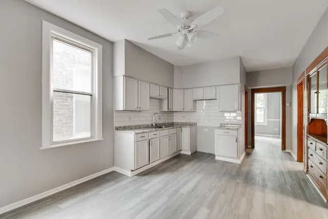 a kitchen with white cabinets and wooden floor