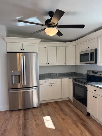 a kitchen with cabinets stainless steel appliances and wooden floor