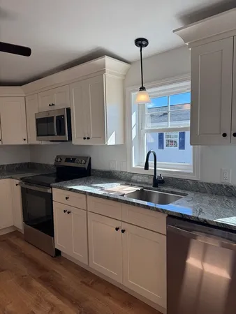 a kitchen with granite countertop a sink stainless steel appliances and white cabinets
