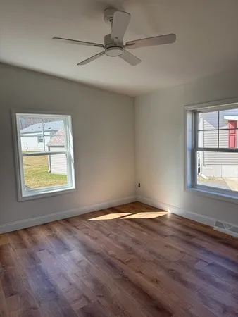 a view of an empty room with wooden floor and a window