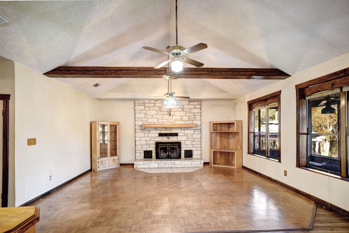 113 My Road Bastrop, TX 78602 - Photo 12 of 35 Unfurnished living room with a textured ceiling, a fireplace, and a ceiling fan