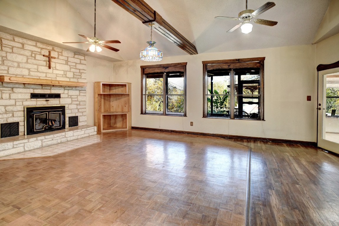 113 My Road Bastrop, TX 78602 - Photo 13 of 35 Unfurnished living room featuring ceiling fan, plenty of natural light, a fireplace, high vaulted ceiling, and parquet floors